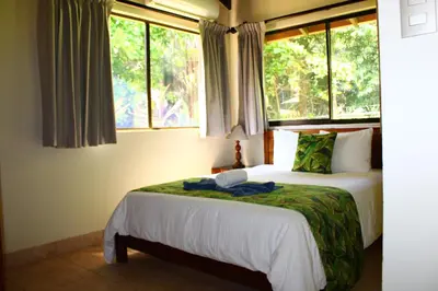a bedroom with two beds and two windows at La Foresta Nature Resort in Quepos
