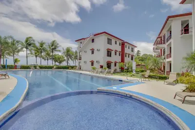 a swimming pool in a resort with chairs and palm trees at Bahia Azul 7A in Jacó