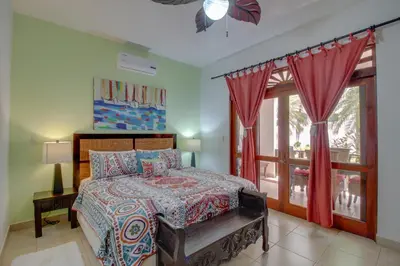 a bedroom with a bed with red curtains and a window at Bahia Azul 7A in Jacó