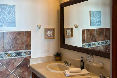 a bathroom with a sink and a large mirror at La Paloma Blanca B3 in Jacó