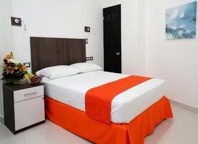 a bedroom with a large bed with an orange blanket at Hotel Milan Costa Rica in San José