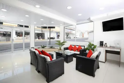 a living room with a couch and chairs and a tv at Hotel Milan Costa Rica in San José