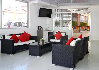 a living room with black chairs with red pillows at Hotel Milan Costa Rica in San José