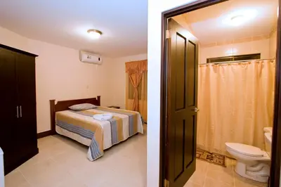 a bedroom with a bed and a bathroom with a toilet at Hotel El Cerro in Liberia