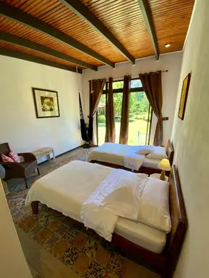 a bedroom with three beds and a chair and a couch at YerbaBuena Lodge in Monteverde Costa Rica