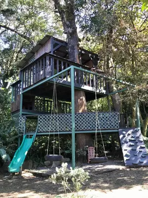 a tree house with a swing and a slide at YerbaBuena Lodge in Monteverde Costa Rica
