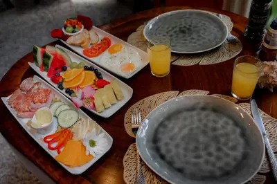 a wooden table with plates of food and glasses of orange juice at Samara Chillout Lodge - Adults only in Sámara