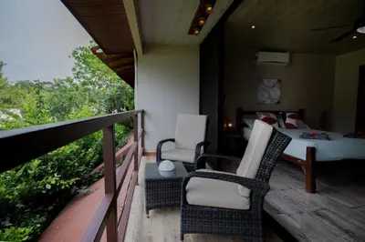 a bedroom with a bed and chairs on a balcony at Samara Chillout Lodge - Adults only in Sámara
