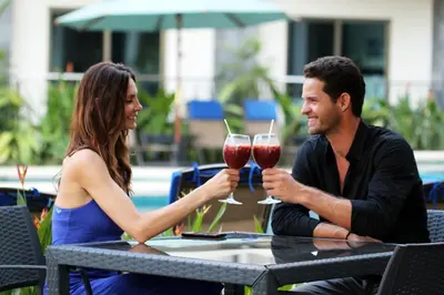 a man and woman sitting at a table with glasses of wine at PACIFIC SUITES Boutique Hotel and Bistro in Jacó