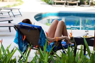a woman laying in a chair next to a pool at PACIFIC SUITES Boutique Hotel and Bistro in Jacó