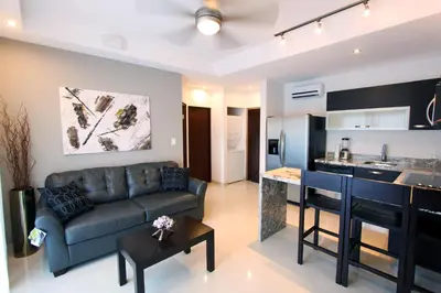 a living room with a couch and a kitchen at PACIFIC SUITES Boutique Hotel and Bistro in Jacó