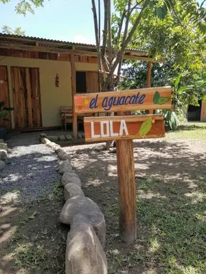 a wooden sign in front of a lodge at El Gecko Hotel & Tours in Paquera