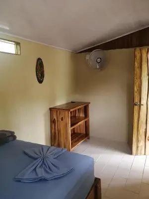 a bedroom with a blue bed and a wooden cabinet at El Gecko Hotel & Tours in Paquera