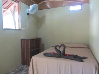two swans sitting on a bed in a room at El Gecko Hotel & Tours in Paquera