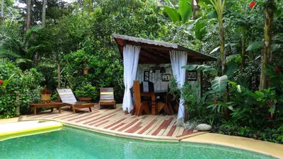 a wooden deck with a table and chairs next to a pool at Dos Casitas in Ojochal