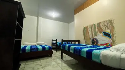 a bedroom with two beds and two chairs at Mi Casa Tica in Monteverde Costa Rica
