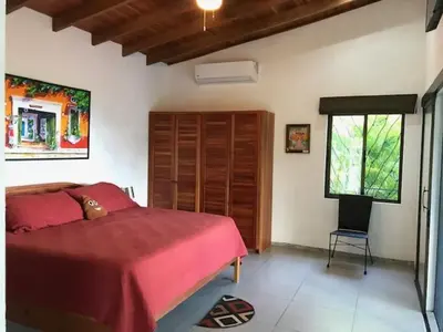 a bedroom with a red bed and a chair at Villas Lambeau Ocean View 1 in Uvita