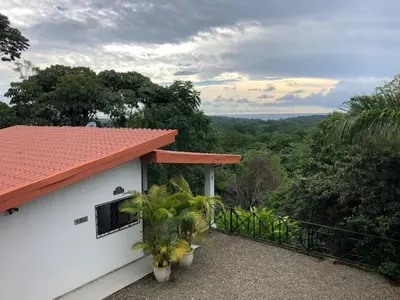 a white house with a balcony with plants at Villas Lambeau Ocean View 1 in Uvita