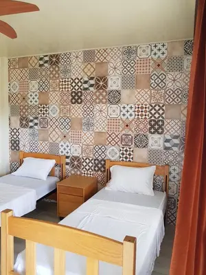 two beds in a room with a tiled wall at Hotel Las Palmas de OSA in Ciudad Cortés