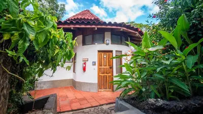a small white house with a wooden door at Hotel Luna Llena in Tamarindo