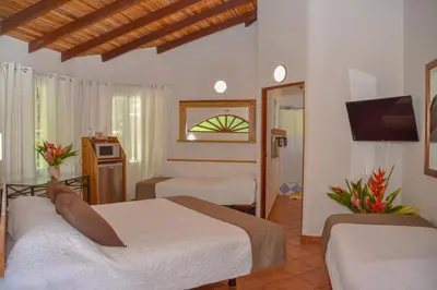 a hotel room with two beds and a tv at Hotel Luna Llena in Tamarindo