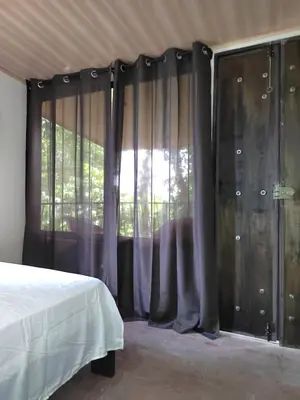 a bedroom with a bed and a window with curtains at Salamandra Costa Rica in Jiménez