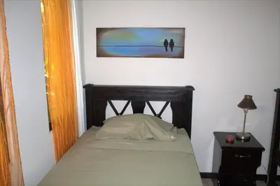 a small bedroom with a bed and a painting on the wall at Salamandra Costa Rica in Jiménez