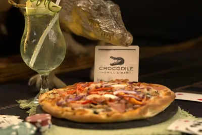 a pizza on a table next to a wine glass at Hotel Villas Rio Mar in Dominical