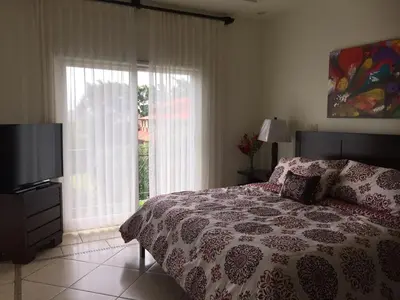 a bedroom with a bed and a tv and a window at Matapalo Diria #504 Amazing Condo-Ocean View in Tamarindo