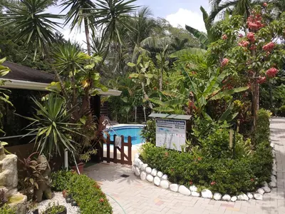 a garden with a swimming pool and trees and a sign at Hotel Belvedere Playa Samara Costa Rica in Sámara