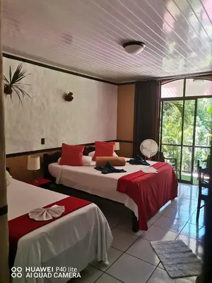 a bedroom with two beds with red and white sheets at Hotel Belvedere Playa Samara Costa Rica in Sámara