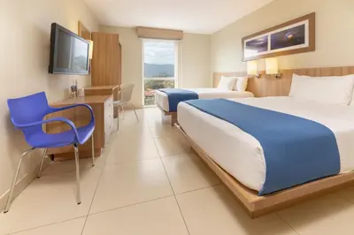 a hotel room with two beds and a blue chair at City Express by Marriott San José Costa Rica in San José