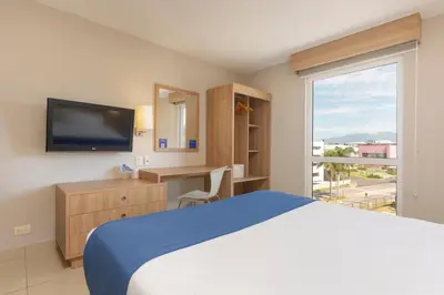 a hotel room with a bed and a tv and a window at City Express by Marriott San José Costa Rica in San José