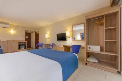a bedroom with a large bed and blue chairs at City Express by Marriott San José Costa Rica in San José