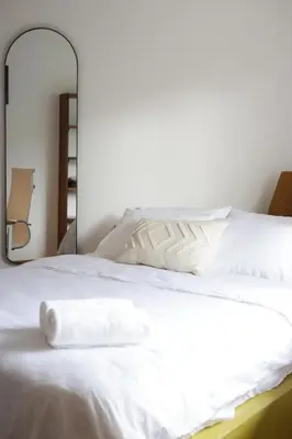 a white bed with white sheets and a mirror at Outsite Santa Teresa Playa in Santa Teresa Beach