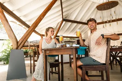 a man and woman sitting at a table in a tent at Mikado Natural Lodge in Playa Avellana