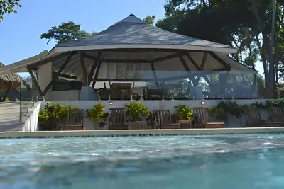 a gazebo with chairs and a swimming pool at Mikado Natural Lodge in Playa Avellana