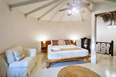 a bedroom with a bed and a couch and a ceiling fan at Paradise Beach Lodge in Mal País