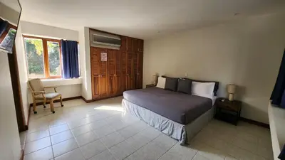 a bedroom with a bed and a chair and a window at La Casa de Cariari Al Golf in Heredia
