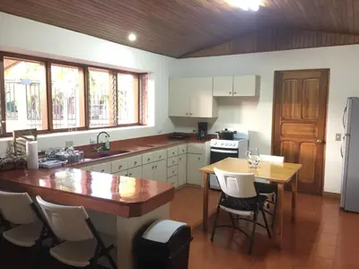 a kitchen with white cabinets and a wooden table at La Casa de Cariari Al Golf in Heredia