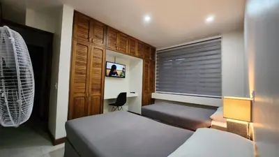 a bedroom with two beds and a window and a chair at La Casa de Cariari Al Golf in Heredia