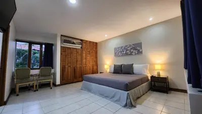 a bedroom with a bed and a table and chairs at La Casa de Cariari Al Golf in Heredia