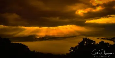 a cloudy sky with the sun shining through the clouds at Magic Mountain Views Studio in Atenas