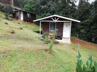 a small cabin on a hill with a grassy yard at Miriam'S Quetzals lodge in San Gerardo de Dota