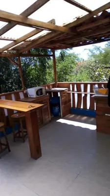 a patio with a wooden table and a wooden pergola at 1 Bedroom G-Land Burnt Toast Surfcamp in Nosara