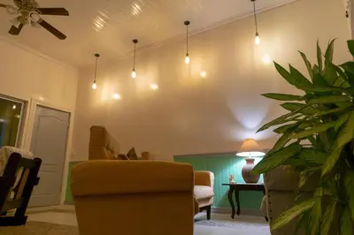 a living room with a couch and a chair and lights at Alice y Juancito Boutique Hotel in Alajuela City