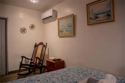 a bedroom with a bed and a chair and a fan at Alice y Juancito Boutique Hotel in Alajuela City