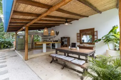 an outdoor kitchen with a wooden table and bench at Blue Surf Sanctuary in Santa Teresa Beach