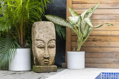 a statue of a face in two pots with plants at Blue Surf Sanctuary in Santa Teresa Beach