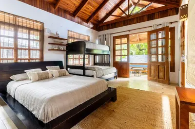 a bedroom with a bed and a desk and windows at Blue Surf Sanctuary in Santa Teresa Beach